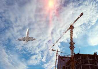 Bottom view of a house with a construction crane and an airplane. sky with white clouds