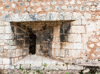 Dramatic image of a old stone fort facade with a window for a cannon, in the old historical Caribbean  colonial district of Santo Domingo,Dominican Republic.