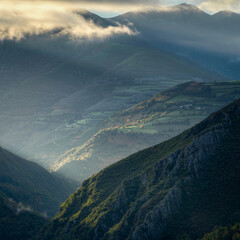 Tangential rays of the dawn sun illuminate villages and meadows between steep slopes