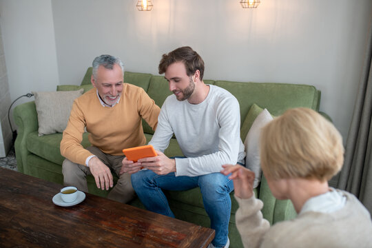 Son visiting parents and showing new photos to them