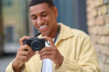 Positive photographer with camera in hands looking happy