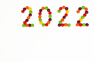 The inscription of the new year 2022 with multi-colored candy pins on a white background, the inscription is at the top. Top view. 