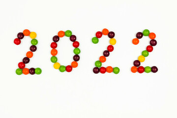 The inscription of the new year 2022 with multi-colored candy pins on a white background. Top view. 