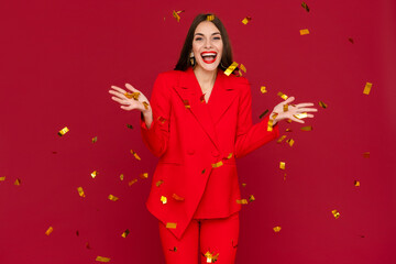 attractive woman celebrating Christmas on red background in confetti