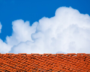 Red roof tiles with white clouds above as background