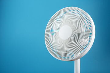 White modern electric fan for cooling the room on a blue background. - obrazy, fototapety, plakaty