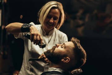 Young bearded man getting beard haircut by hairdresser