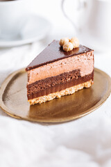 Chocolate hazelnut cake with five layers of biscuit and cream with chocolate glazing on top and whole nuts from Piemont. Served and decorated with coffee in background
