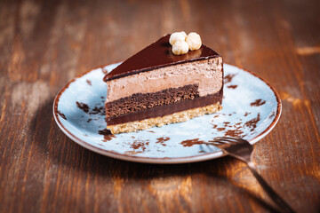 Chocolate hazelnut cake with five layers of biscuit and cream with chocolate glazing on top and...