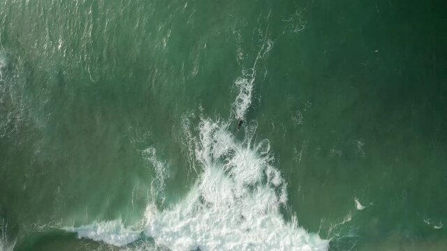Aerial view of a person doing surf and riding waves at sea, Truro, Cornwall, United Kingdom.