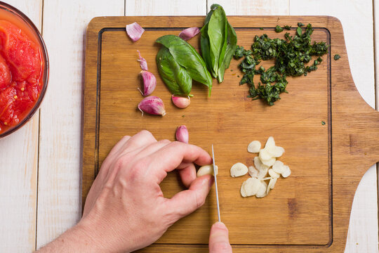 Unrecognizable man chopping garlic for marinara sauce