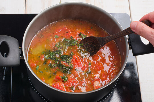 Unrecognizable man cooking marinara sauce on stove