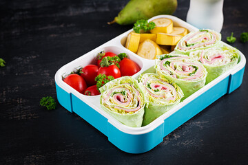 School lunchbox. Healthy lunch box with tortilla wraps, tomatoes, banana, pear and yogurt.