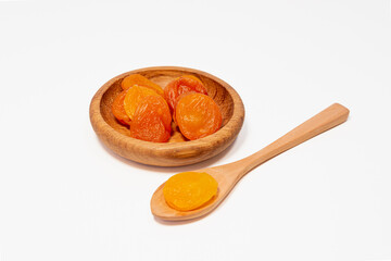Dried apricots in a wooden saucer and a wooden spoon.