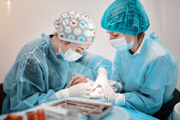 
2 women dentists perform dental implantation operations on a patient in a dental clinic in special clothes
