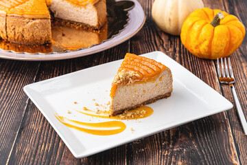 Delicious pumpkin cheesecake in white plate on wooden table