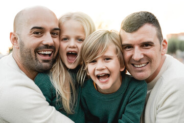 LGBT family outdoor - Happy gay men couple and sons having fun together at city park - Focus on...