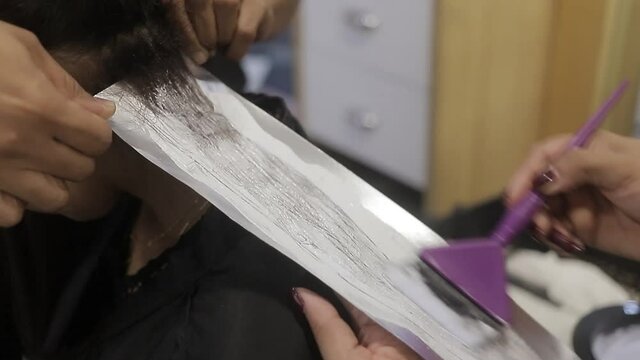 chica estilista aplica tratamiento al cabello de cliente para cambia de color de cabello, negocio de salon de belleza.