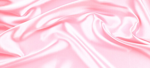 Beautiful pastel pink background with drapery and wavy folds of silk satin material texture. Top...