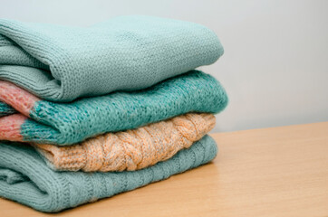 Fototapeta na wymiar Pile of knitted winter clothes on a neutral background, sweaters, knitwear, space for text