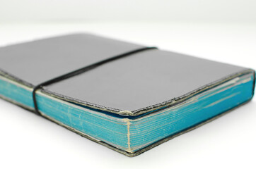 Old Tattered diarie on a white background.closed Diarie in blue tattered cover with no lettering.