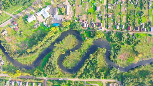 Aerial view landscape of winding small river among the small town, stream in green field