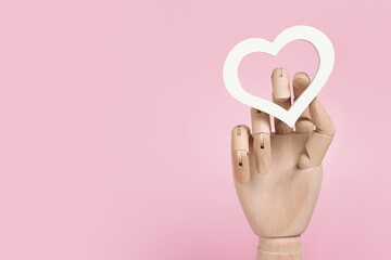 Romantic banner for valentine's day. White heart in a wooden hand on a pink pastel background. Place for your text, copy space.
