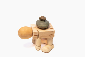 A wooden man carries large stones on his back, hard work of a man.
