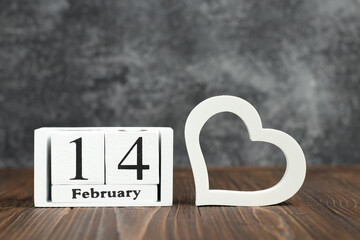 White cube calendar with date of February 14 with heart on wooden background. Congratulatory photo for valentine's day for sms mailings, cards and banners.