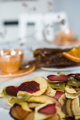 Fruit marshmallow and paste on a white table and white kitchen with dry oranges and dry flowers, cup ot tea on the table