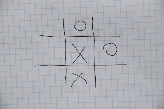 game of tic-tac-toe is drawn with a pen on a crumpled notebook in a cage, play and rest, children's game of tic-tac-toe - Powered by Adobe