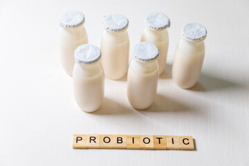 Small bottles with probiotics and prebiotics dairy drink on white background. Production with...