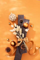 Moderne, weihnachtliche Dekoration im Lichtspiel mit Trockenblumen, Sternen und Kugeln in gold auf...