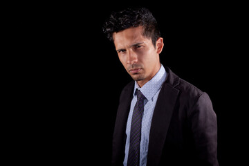 Attractive businessman posing for the camera with sexy look. Young latin man wearing elegant clothes isolated on black background.