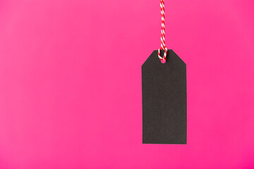 Blank black or dark grey price tag isolated on pink background. Black friday, sale, discount concept.