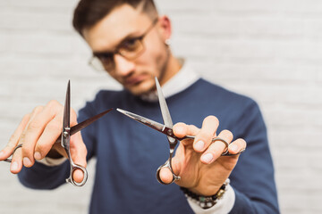 Professional barber hair stylist holds two pairs of scissors in each hand
