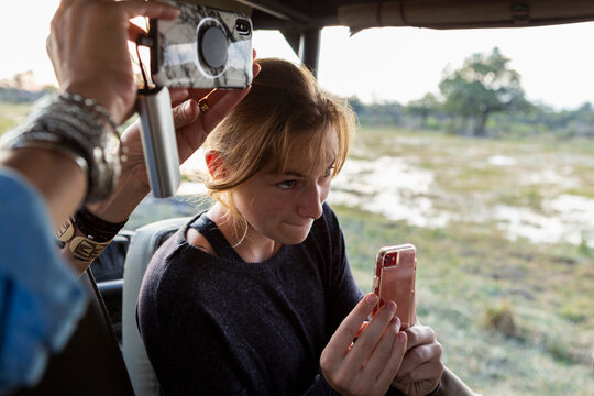 Teenage girl using smart phone to take a picture during a safari jeep drive. 