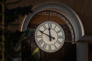The hands of the clock 10 minutes to 12 on the large white dial of the outdoor clock on the wall