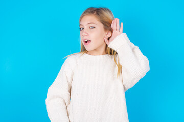 Oh my God! Funny astonished caucasian little kid girl wearing wool jersey over blue background...
