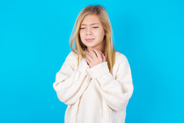 Sad caucasian little kid girl wearing wool jersey over blue background feeling upset while spending...