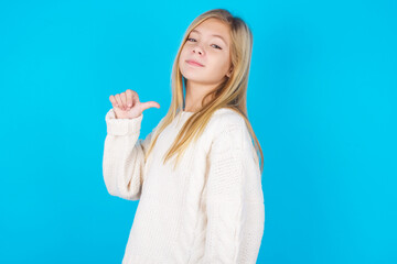 Closeup of cheerful caucasian little kid girl wearing wool jersey over blue background looks...
