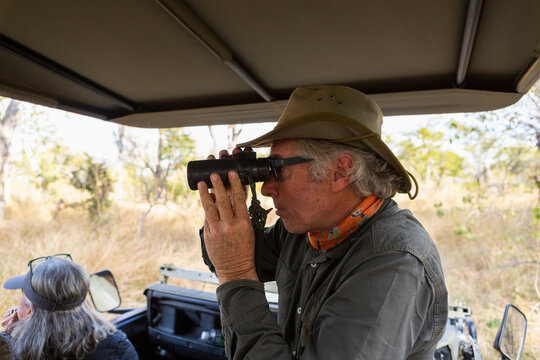 Safari guide using binoculars in a jeep with a family 