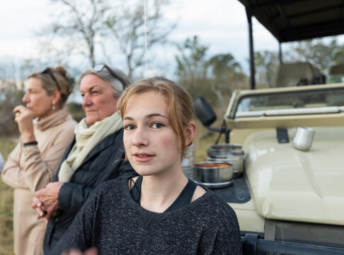 Three generations of women, a grandmother, mother and teenage girl by a safari jeep