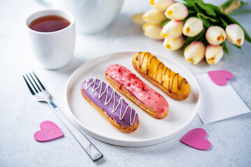 Fresh multicolored eclairs with chocolate glaze