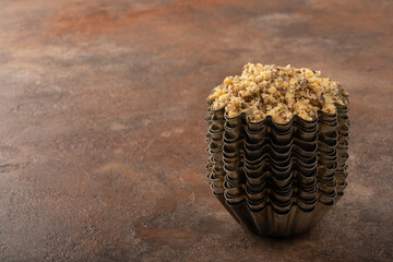 Close-up shot of a crushed walnut in a vintage baking dish, a pyramid of molds on a harmonious rusty background. Copy space view.