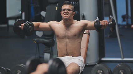 Fototapeta na wymiar Arab male athlete improves his shoulders with dumbbell breeding.