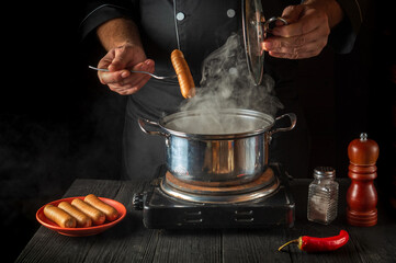 The cook cooks Vienna sausage in a saucepan. Working environment in the restaurant kitchen....