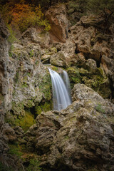 Vertical photo of a beautiful waterfall in a natural environment of rocks with a magical atmosphere in the Natural Park of Sierra de Cazorla, Jaén, Spain