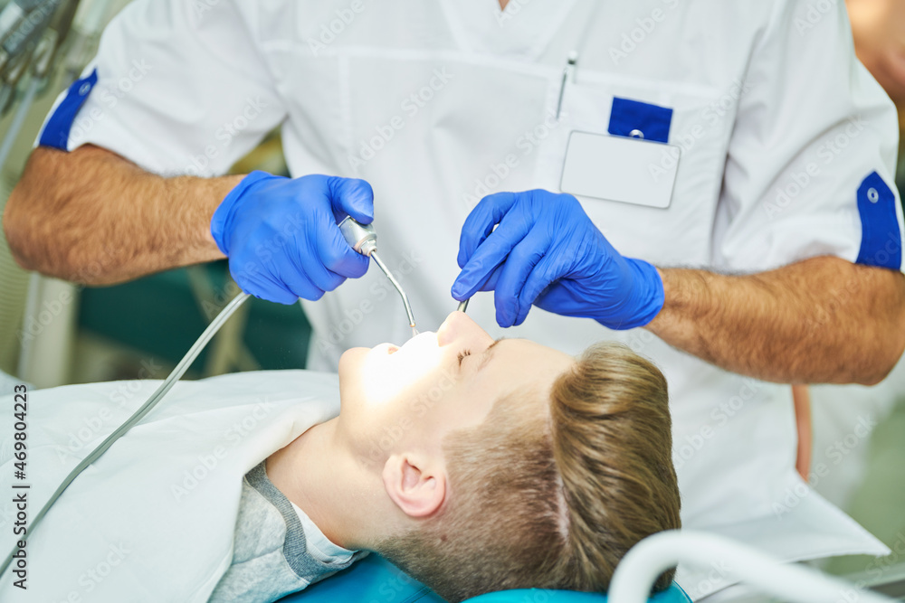 Wall mural male dentist at work with young patient