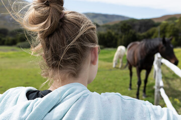 Teenage girl watching horses in a field